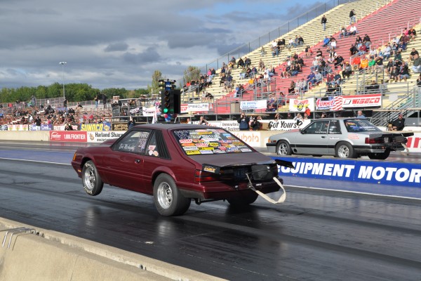 a pair of ford fox body mustangs launching at a drag strip
