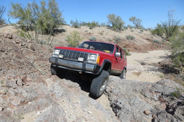 jeep cherokee xj climbing rocks on a desert trail