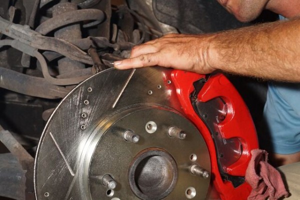 man installing a disc brake rotor and caliper onto a chevy Silverado