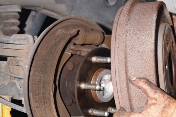 man removing drum from brake shoes and hub