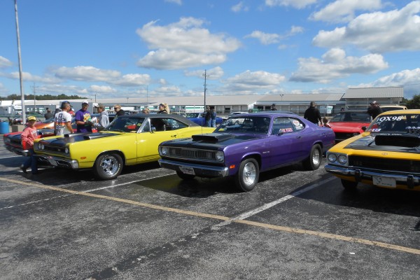 a trio of classic mopar musclecars at a car show