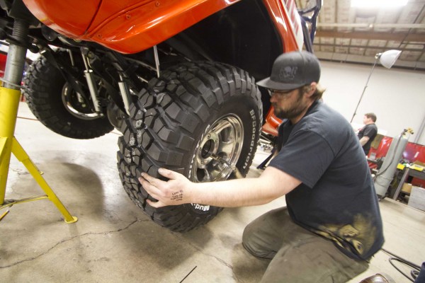 man fitting wheel onto ford bronco race truck