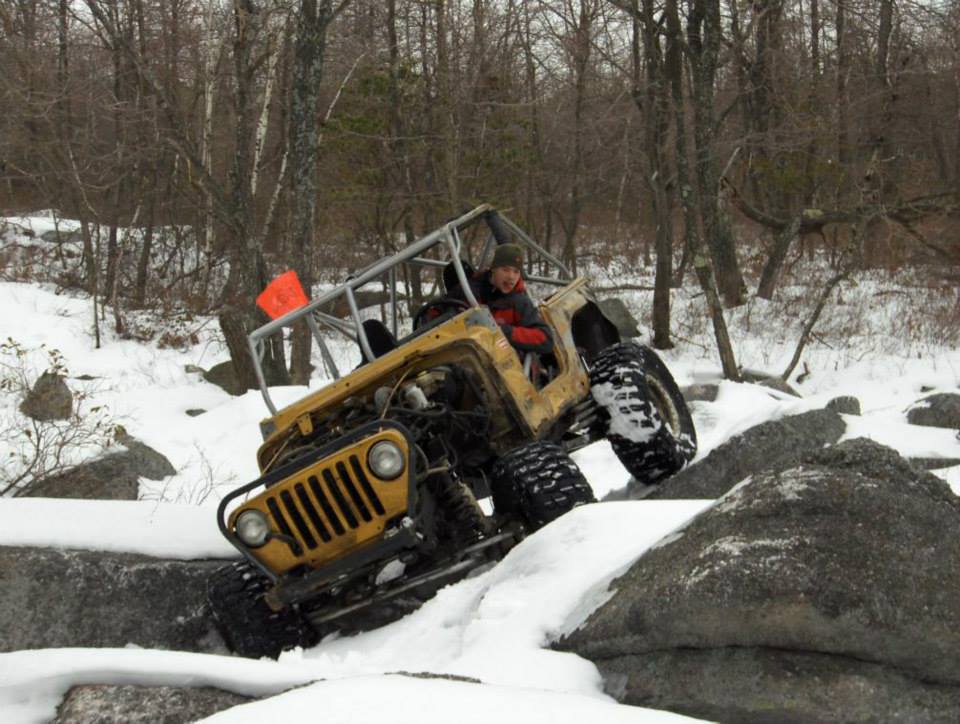 man driving jeep cj through snowy trail