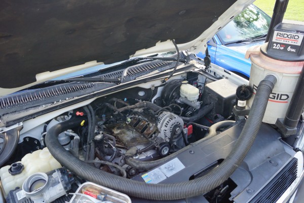 using a vacuum to clean the engine bay of a chevy truck