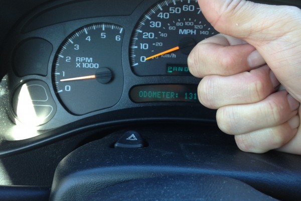 man gives thumbs up in front of a car speedometer