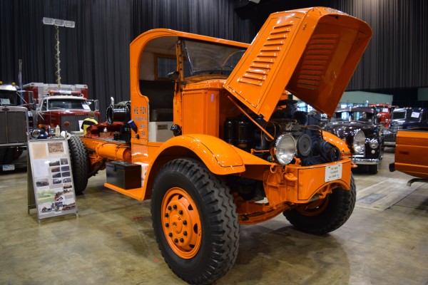 vintage orange semi truck on display at indoor car show