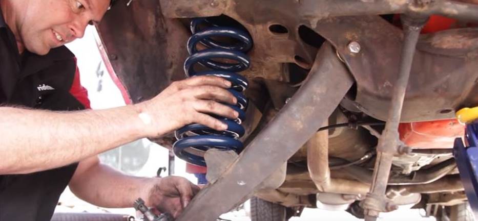 man installing automotive coil spring