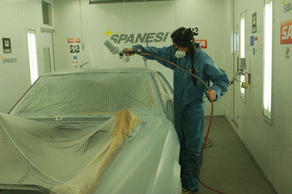 painter spraying pain on the body of an AMC AMX car