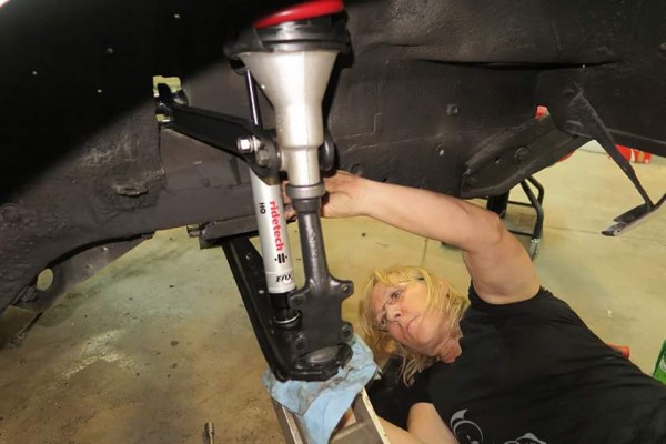 woman installing shocks and suspension parts in an AMC AMX