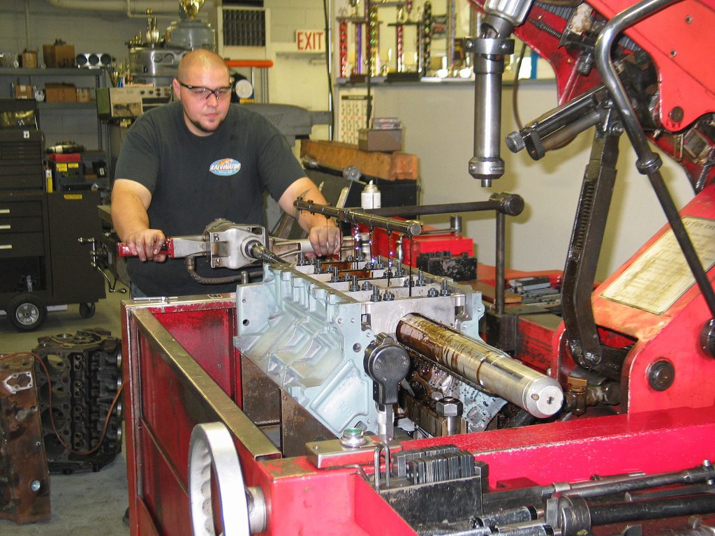 man honing cylinder bores in an engine machine shop