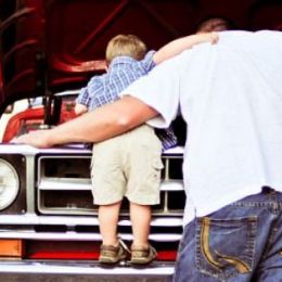 father and son looking under hood of truck