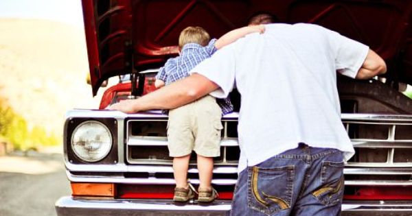 father and son looking under hood of truck