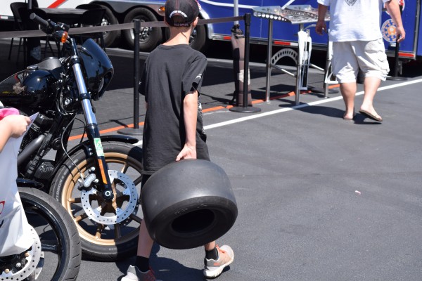 boy carrying a tire in an nhra pit area