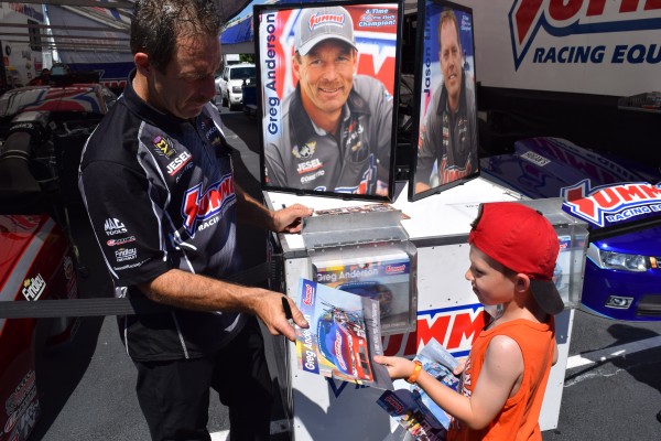 greg anderson giving an autograph to young nhra fan