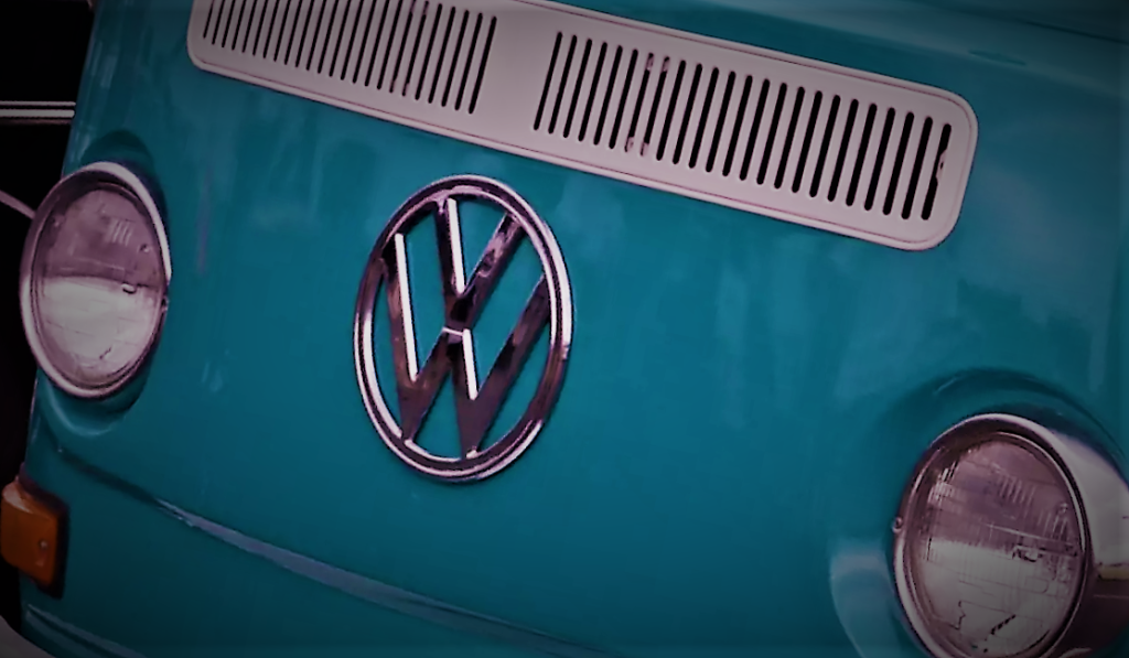 Stylized close-up photo of a VW emblem on the front of a 1960s-era type 2 transporter bus