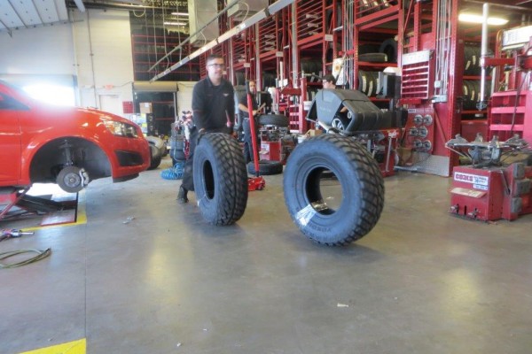 man rolling tires through a garage shop