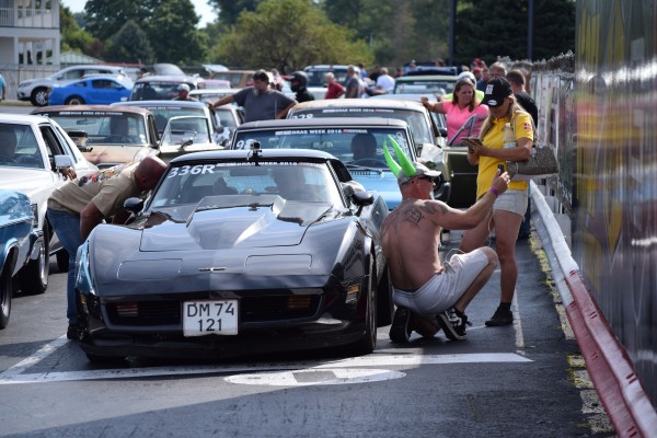 people and cars in staging lanes at drag strip event