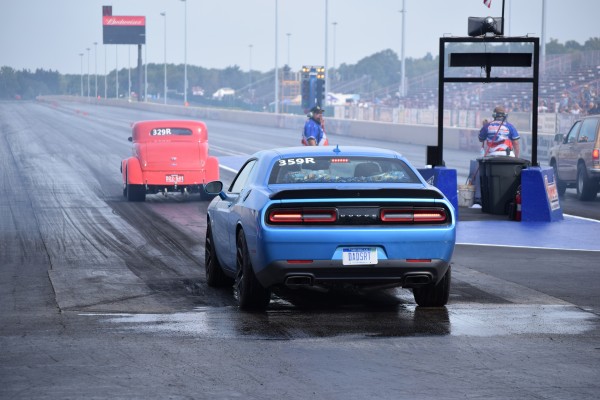 late model dodge challenger getting ready to stage behind a hot rod on a dragstrip