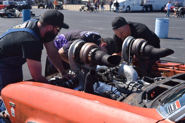 men working on win turbo engine in a vintage muscle car