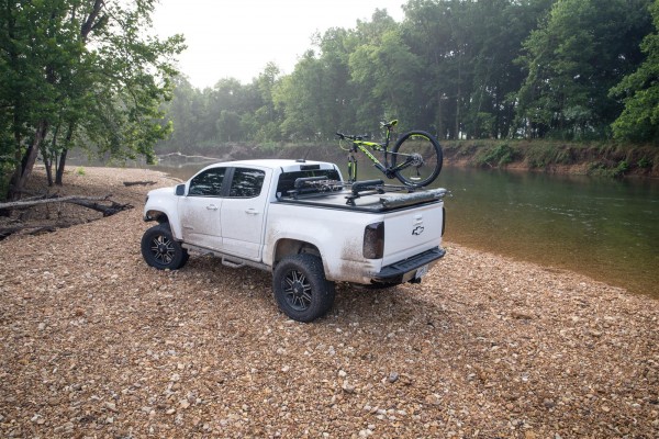 white truck with bike rack parked near a stream