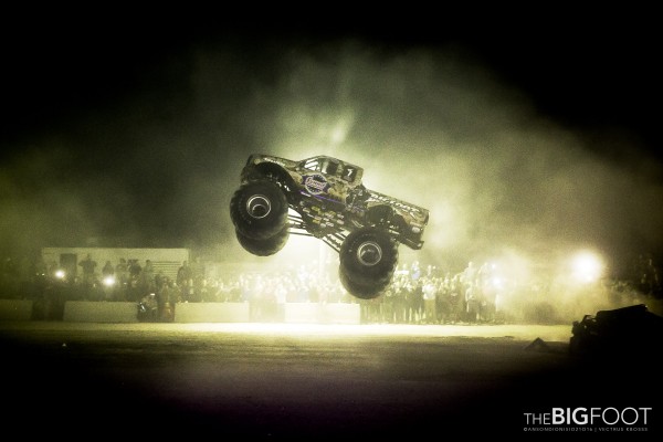 bigfoot monster truck jumping over crushed cars at night