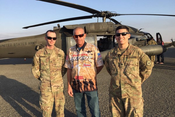men posing for picture near military blackhawk helicopter