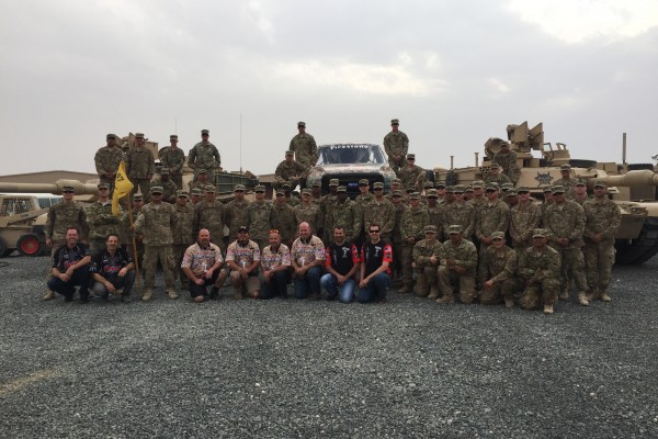 group picture at military base with bigfoot monster truck and tanks