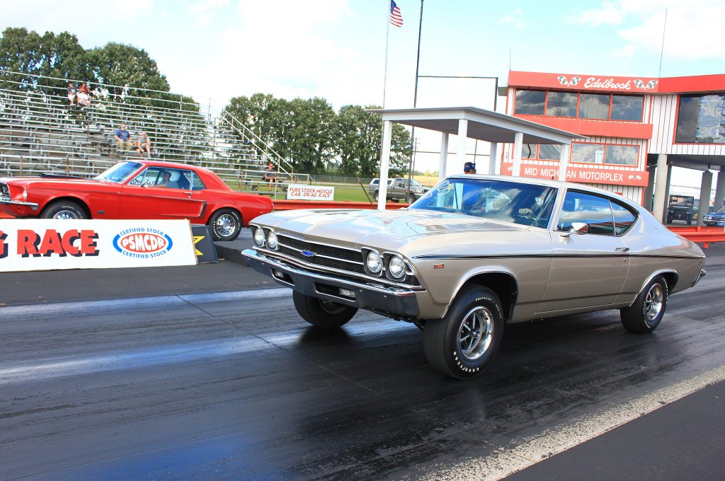 two vintage cars launching at a drag strip