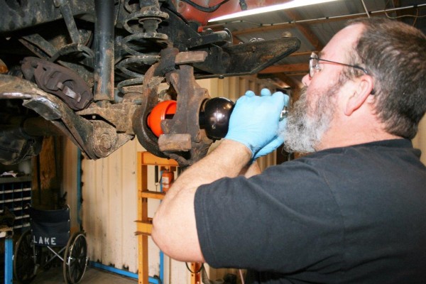man fitting suspension parts through a steering knuckle