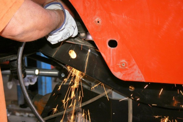 man cutting welds off a jeep wrangler frame