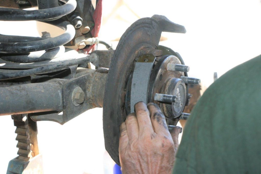 man fitting drum brake shoes onto a jeep wrangler