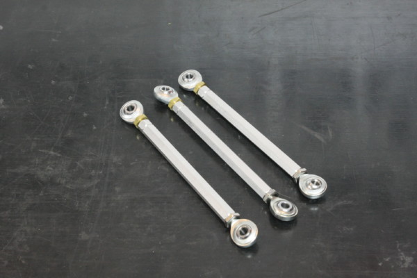 three rod ends and shafts on a workbench