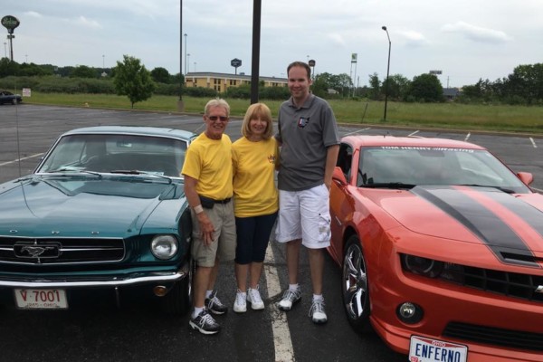 group of people near a ford mustang and chevy camaro