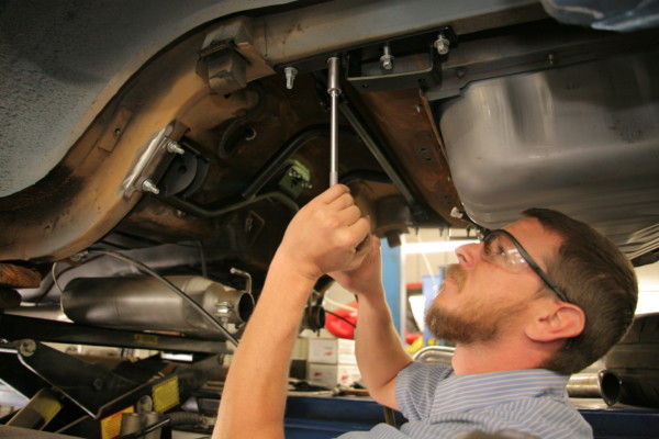 man bolting up suspension bracket in 1968 ford mustang