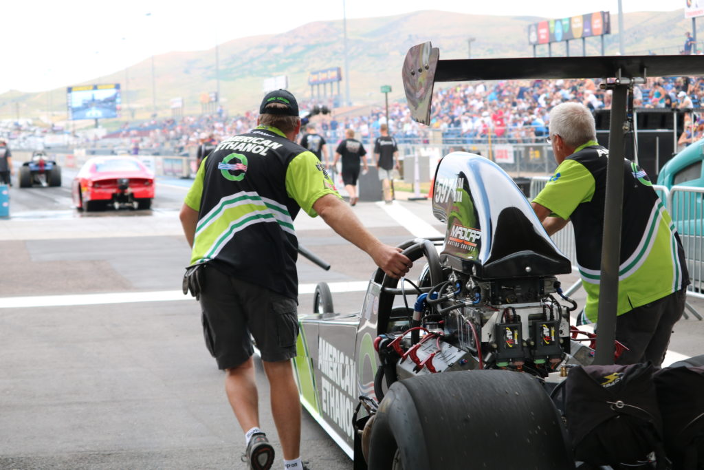 top fuel drag race team pushing car to starting line