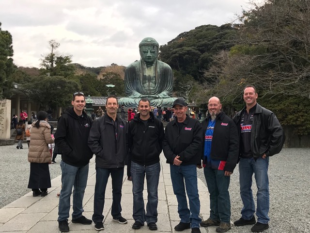 team summit nhra drivers pose with Buddhist statue in japan