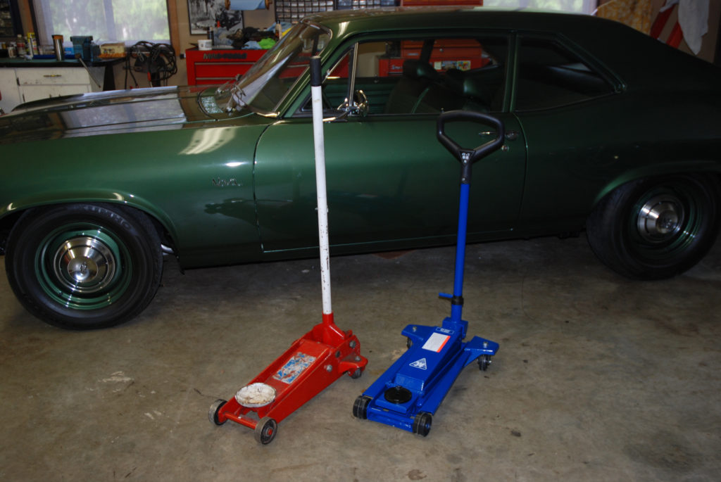 a apir of floor jacks standing side by side next to a chevy nova