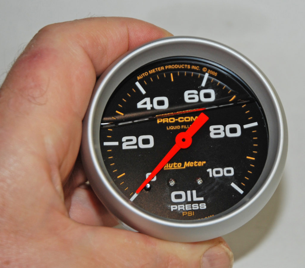 man holding a liquid filler oil pressure gauge