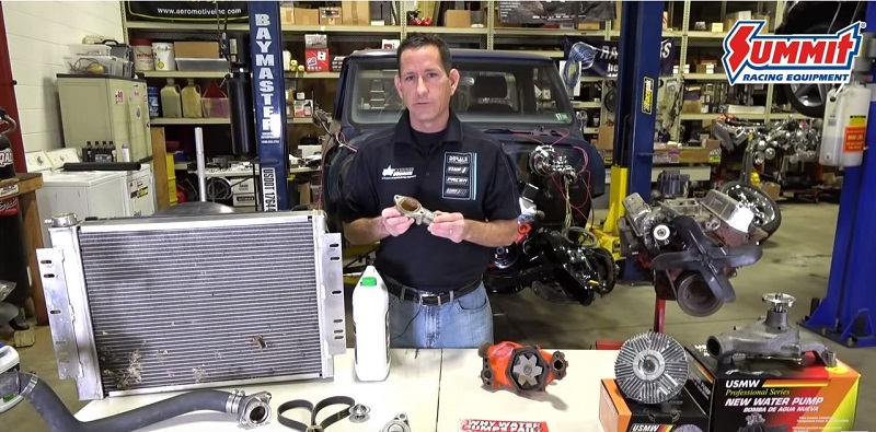 man holding automotive cooling system components in a garage shop