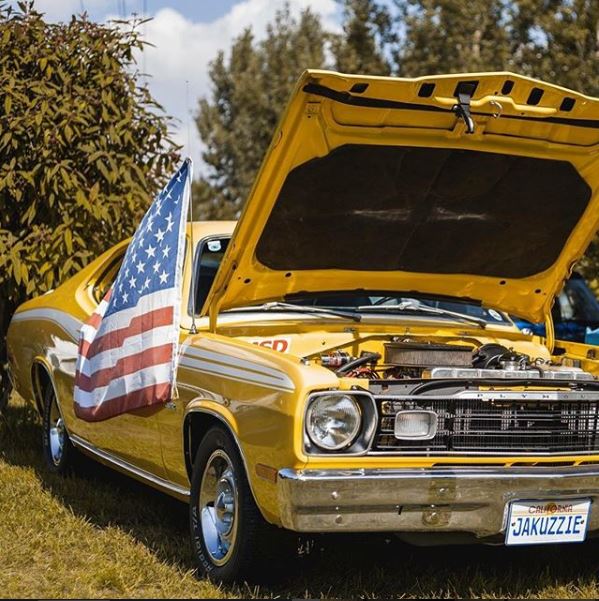 yellow plymouth duster muscle car with american flag