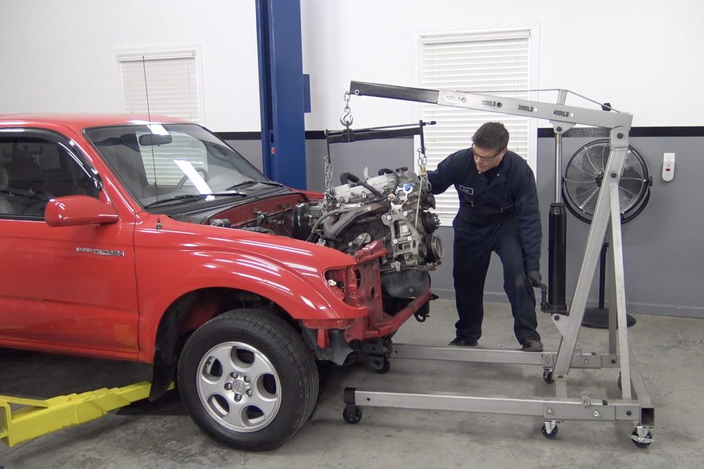 man removing engine from a toyota tacoma