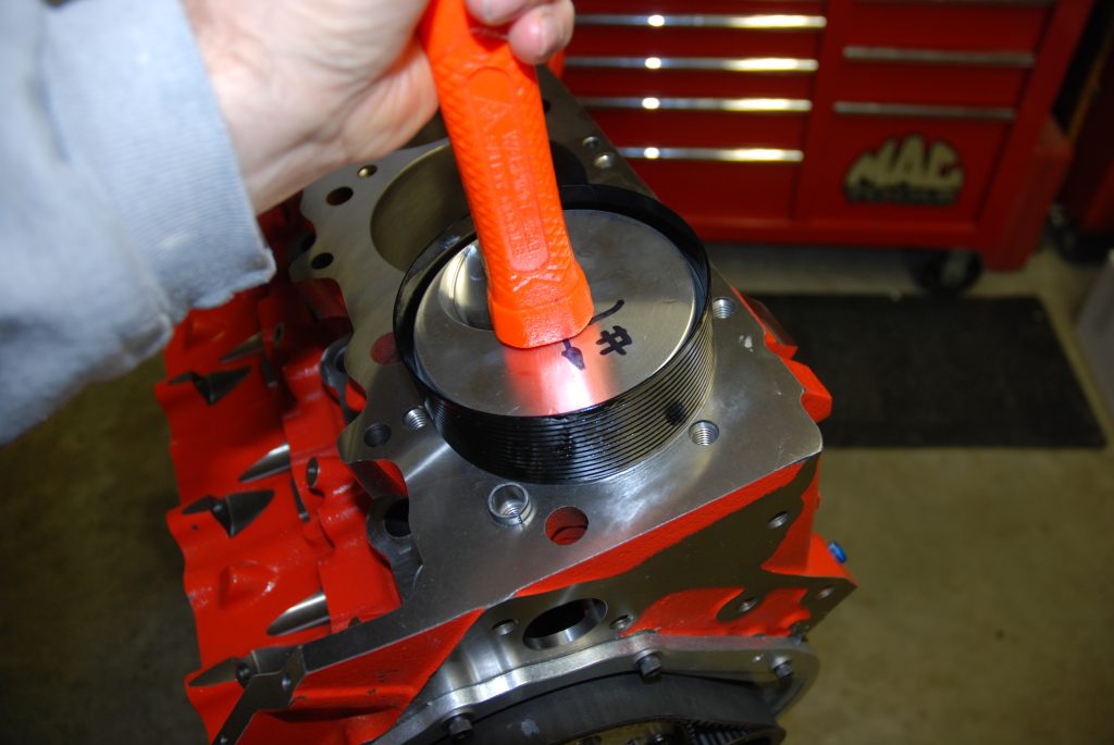 using handle end of a hammer to install a piston into an engine