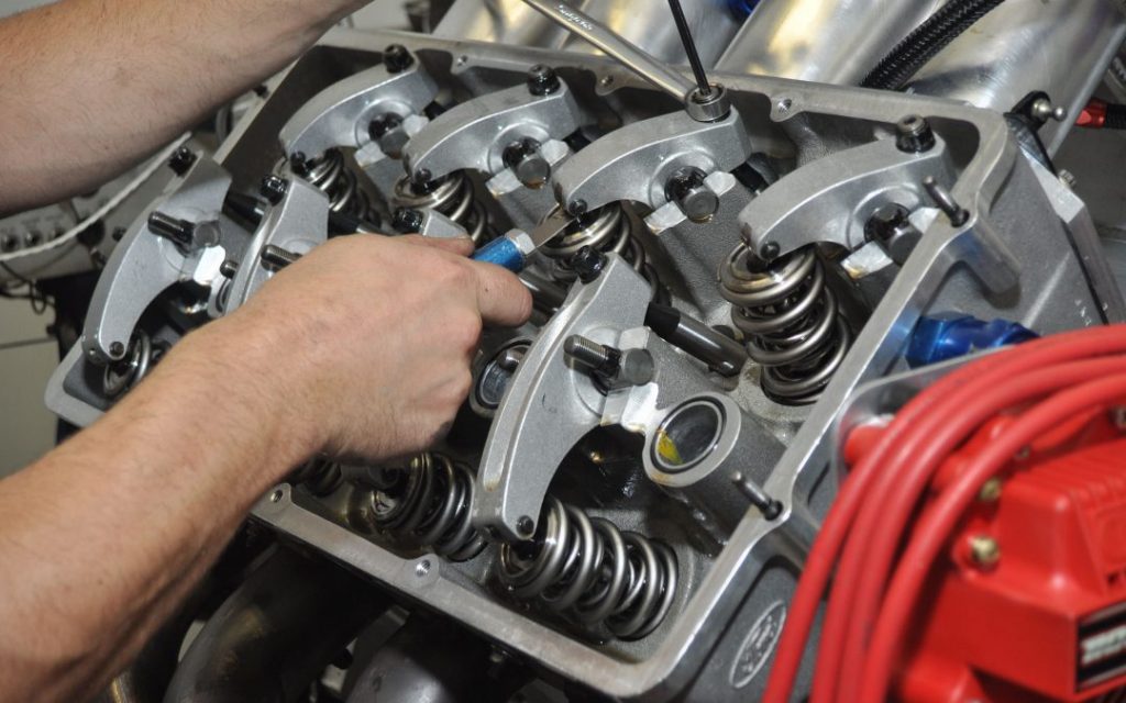 mechanic adjusting valve lash on a rocker in an engine cylinder head