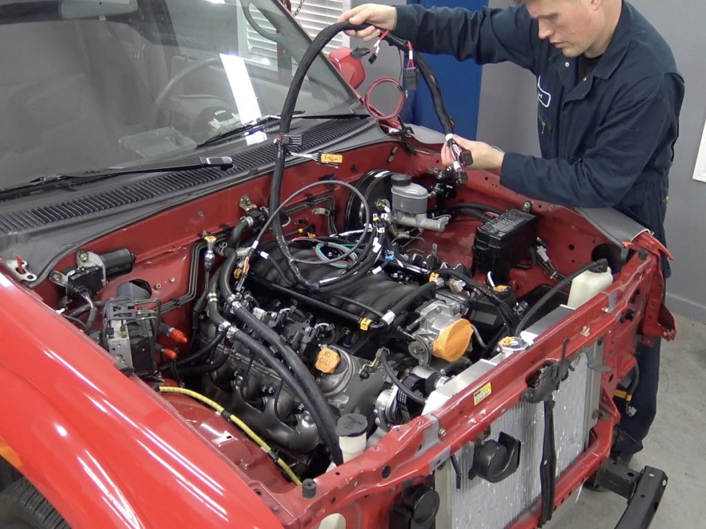 man running plumbing kit in engine bay of a toyota tacoma truck with an ls engine swap