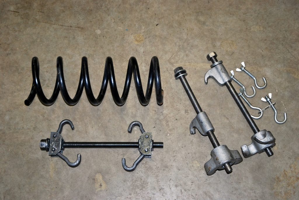 collection of coil spring compressor tools on garage floor