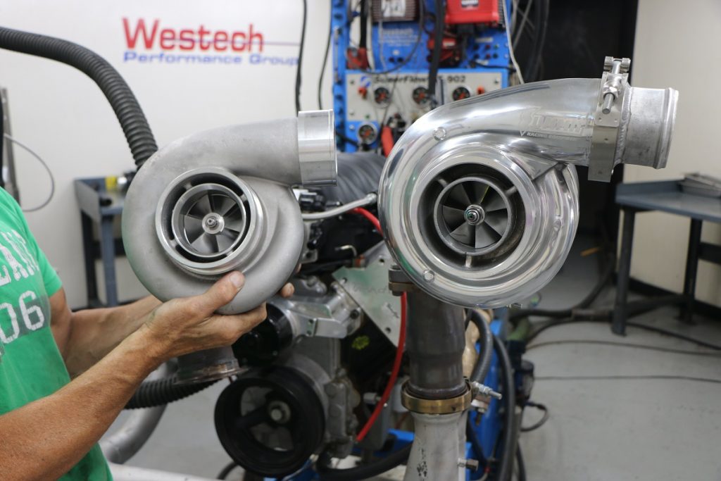 a man comparing two engine turbos side by side