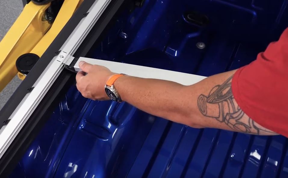 man installing a pickup truck tonneau cover rail