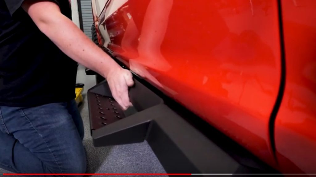 man fitting rock sliders truck steps to ford f150