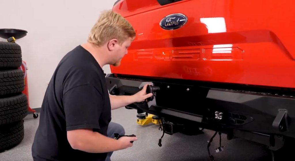 man installing aftermarket rear bumper on ford f-150 truck