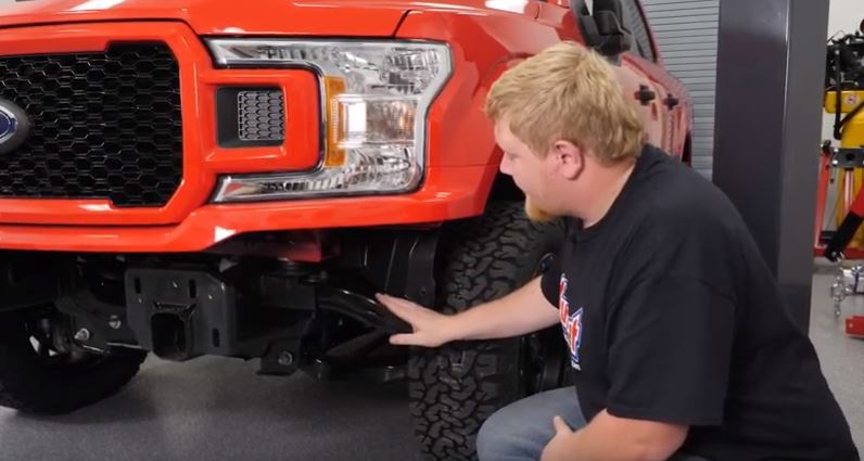 man removing bumper of ford f-150 truck
